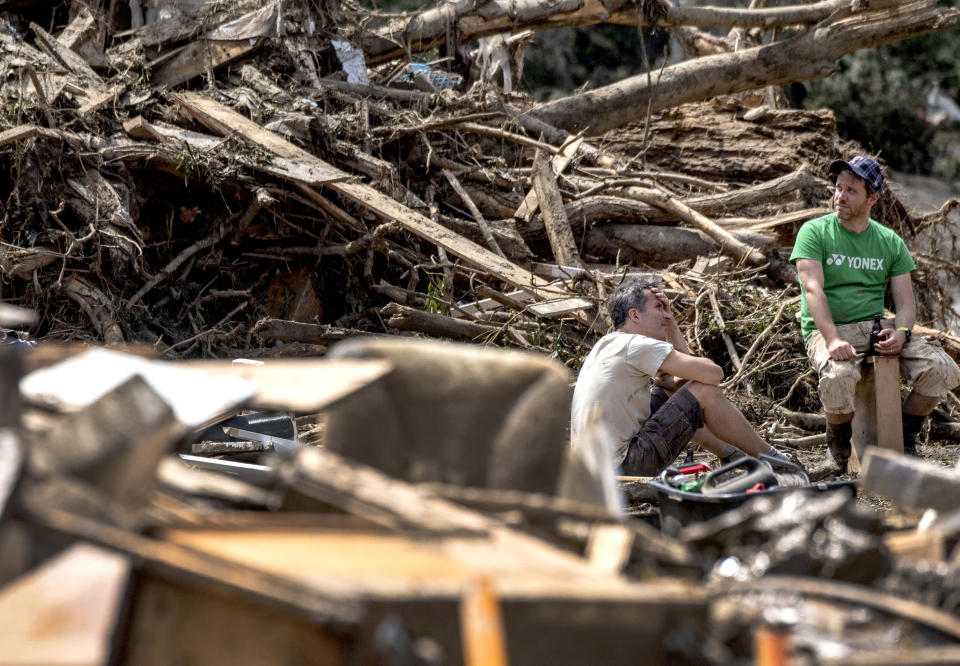 Residents are seen between debris in Marienthal, western Germany, Sunday, July 18, 2021. Heavy rains caused mudslides and flooding in the western part of Germany. Multiple have died and are missing as severe flooding in Germany turned streams and streets into raging, debris-filled torrents that swept away cars and toppled houses. (Boris Roessler/dpa via AP)