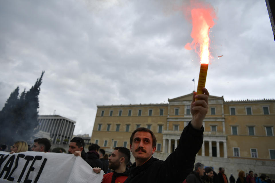 A protester holds a smoke flare during a rally in Athens, Greece, Wednesday, Feb. 28, 2024. Widespread strikes in Greece disrupted transport services Wednesday, halting ferries and trains, in protests timed to coincide with the anniversary of a deadly rail crash a year ago. (AP Photo/Michael Varaklas)