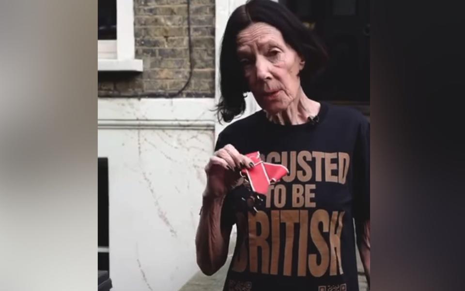 The designer wears a T-shirt saying 'disgusted to be British' before throwing her CBE in the bin