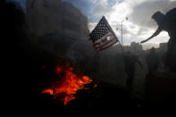 <p>A Palestinian protester prepares to burn a U.S. flag during clashes with Israeli troops at a protest against President Donald Trump’s decision to recognize Jerusalem as the capital of Israel, near the Jewish settlement of Beit El, near the West Bank city of Ramallah, Dec. 7, 2017. (Photo: Mohamad Torokman/Reuters) </p>