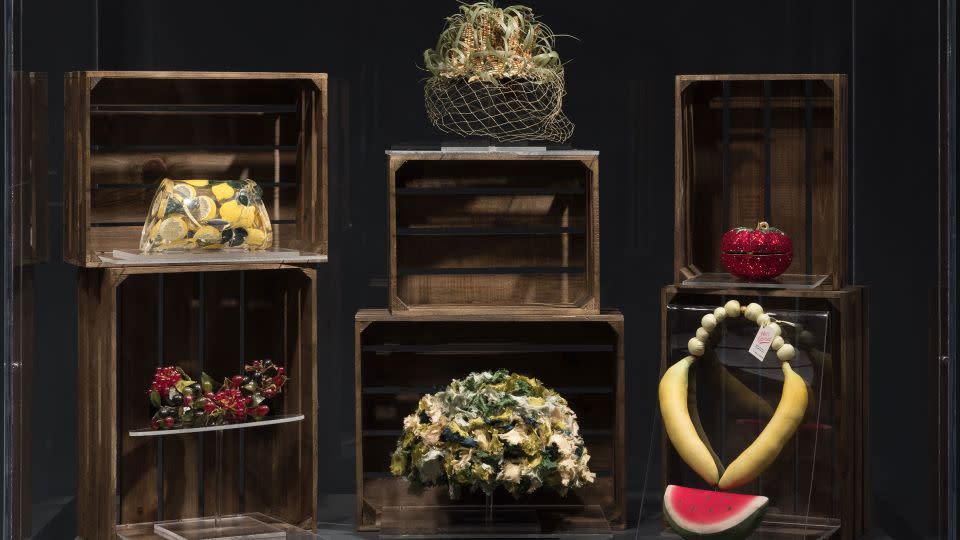 A display in the "Food & Fashion" exhibition features accessories including a lemon-patterned Lucite handbag (top left) by artist Joyce Francis, a corn cob-topped hat (center) by the milliner Benjamin B. Green-Field and a chunky necklace resembling watermelon, bananas and grapes (bottom right). - The Museum at FIT