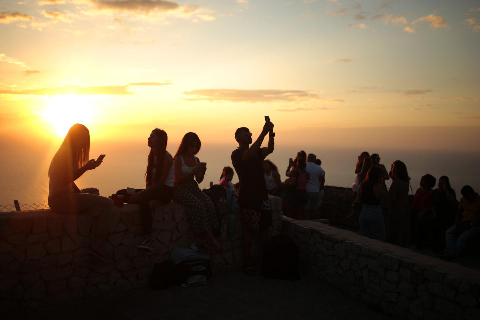 People gather at a viewpoint looking at the mediterranean sea in Palma de Mallorca, Spain, Tuesday, June 16, 2020. Borders opened up across Europe on Monday after three months of coronavirus closures that began chaotically in March. But many restrictions persist, it's unclear how keen Europeans will be to travel this summer and the continent is still closed to Americans, Asians and other international tourists. (AP Photo/Joan Mateu)