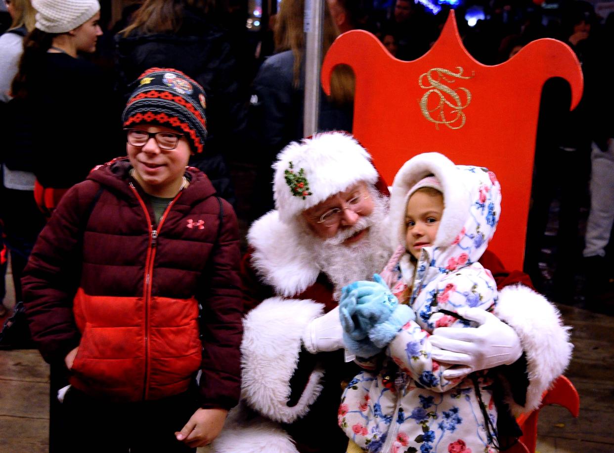 Santa takes time to have his photo taken with Jaice and Nalaya Doss of Creston on Friday night at Window Wonderland.
