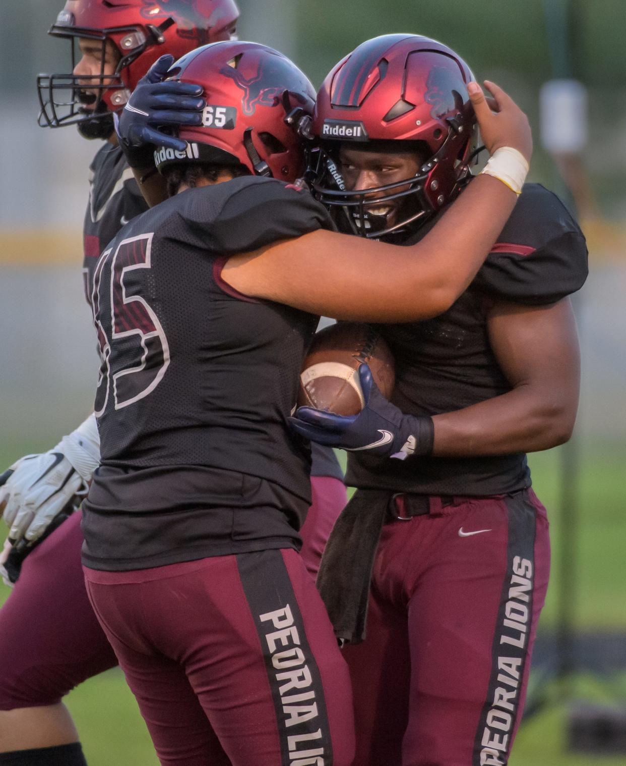 Peoria High's Malachi Washington, right, and Travanti Brown embrace after a touchdown against Metamora in the first half Friday, Aug. 26, 2022 at Peoria Stadium.