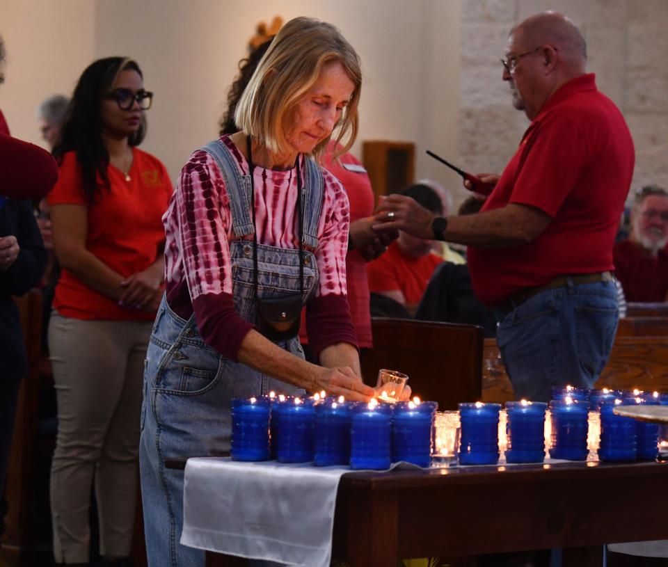 Mary McAuliffe, a parishioner at Our Lady of Lourdes Catholic Church, places a votive candle on the table.