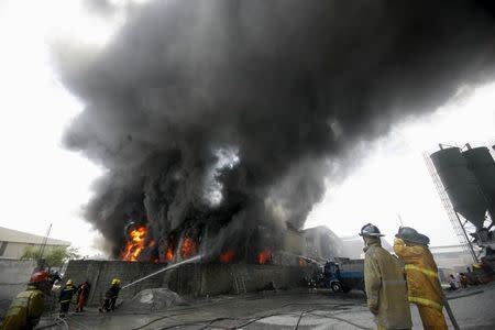 Firefighters attempt to control a raging fire at a factory that manufactures slippers in Valenzuela City, north of Manila May 13, 2015. REUTERS/Al Falcon