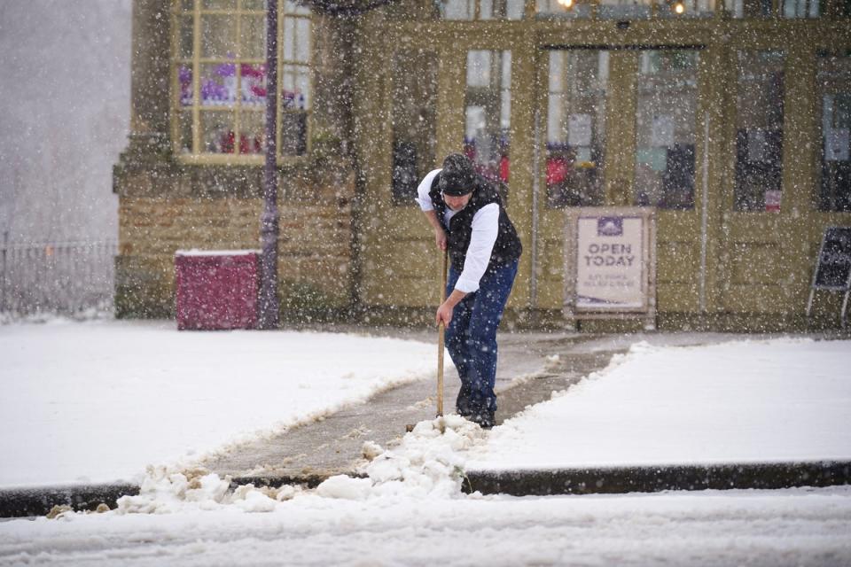 A person clears snow in front of the Opera House in Buxton, Peak District. (PA)