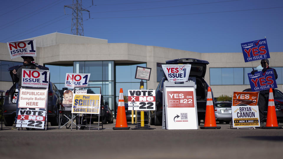 People gather in the parking lot of the Hamilton County Board of Elections as people arrive for early in-person voting, in Cincinnati, Thursday, Nov. 2, 2023. They urge people to vote for or against different issues, including the measure known as Issue 1. Issue 1 is the only abortion question on any state ballot this year. (AP Photo/Carolyn Kaster)