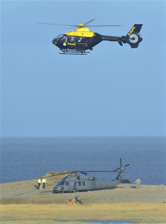 A Pave Hawk helicopter (bottom), military personnel and emergency services attend the scene of a helicopter crash on the coast near the village of Cley in Norfolk, eastern England January 8, 2014. REUTERS/Toby Melville