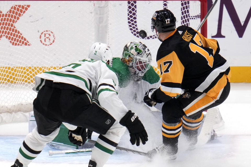 Pittsburgh Penguins' Bryan Rust (17) gets a shot for a goal past Dallas Stars goaltender Jake Oettinger, center, with Jani Hakanpaa (2) defending during the first period of an NHL hockey game in Pittsburgh, Tuesday, Oct. 24, 2023. (AP Photo/Gene J. Puskar)