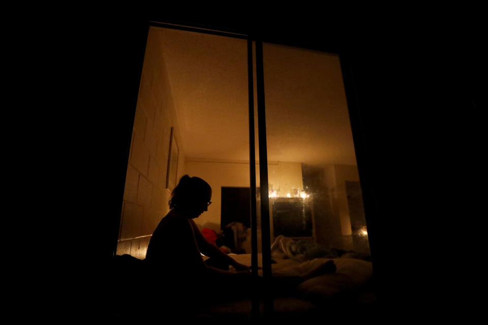 Tasha Whitt sits by a window in her candlelit room at the damaged American Quality Lodge where she continues to live in the aftermath of Hurricane Michael, in Panama City, Fla., Tuesday, Oct. 16, 2018. Whitt, who broke her foot during the storm, worries about looters at night who residents say have taken money, jewelry, food and even rain-soaked clothes from rooms ripped apart and left open to the elements by Michael. (AP Photo/David Goldman)