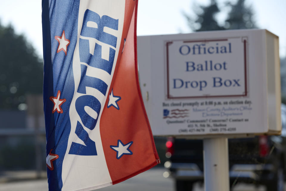 Ballot drop box outside of the Mason County auditors office is seen behind a voter registration banner, Thursday, Oct. 13, 2022, in Shelton, Wash. Washington is an all-mail voting state. (AP Photo/John Froschauer)