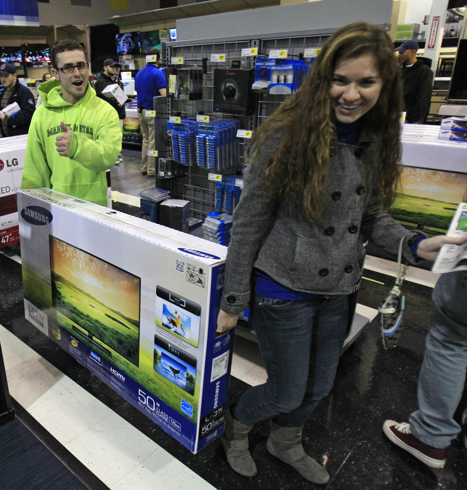 Josh Blankfeld, left to right, gives a thumbs-up as Blankfeld and Erin Burke carry a 50-inch television to the checkout at a Best Buy Friday, Nov. 23, 2012, in Mayfield Heights, Ohio. The store opened at 12 a.m. on Friday. (AP Photo/Tony Dejak)