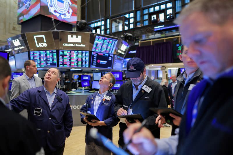 FILE PHOTO: Traders work on the trading floor at the New York Stock Exchange (NYSE) in Manhattan, New York City