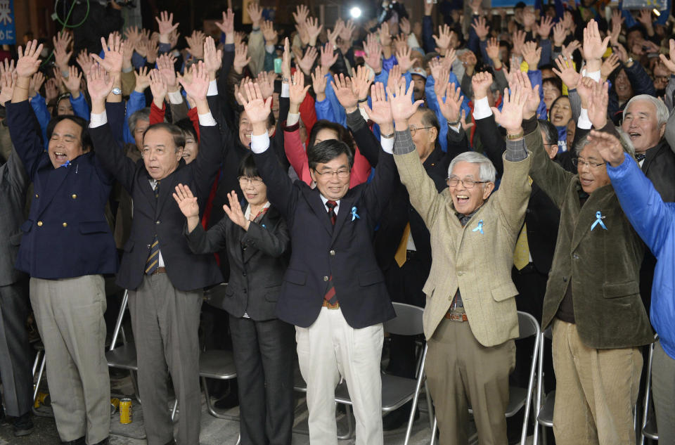 Nago city Mayor Susumu Inamine, third from right in front, celebrates after he was re-elected in the mayoral election in Nago, on the southern Japanese island of Okinawa, Sunday, Jan. 19, 2014. The election is being closely watched from Washington to Tokyo as a referendum on long-delayed plans to move a U.S. air base to the community of 62,000 people. (AP Photo/Kyodo News) JAPAN OUT, MANDATORY CREDIT