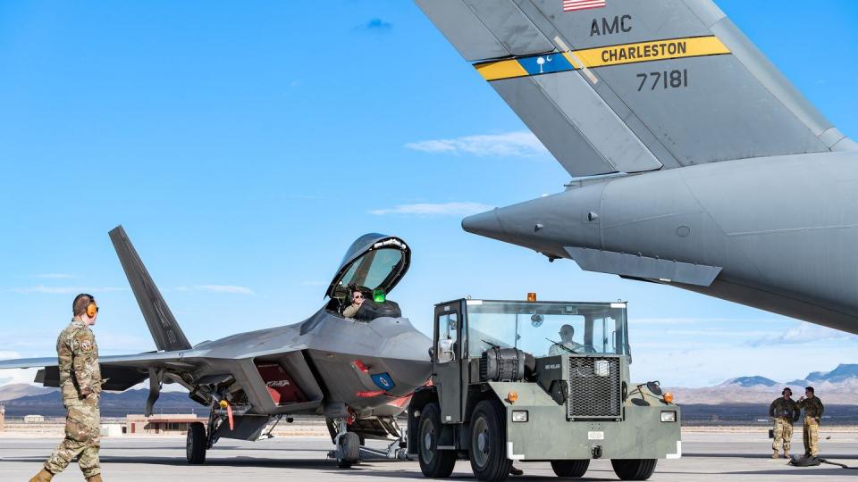 An MB4 tow tractor pulls an F-22 Raptor to be refueled by a C-17 Globemaster III at Nellis AFB, Nev., Feb. 2, 2024. (Tech. Sgt. Curt Beach/Air Force)