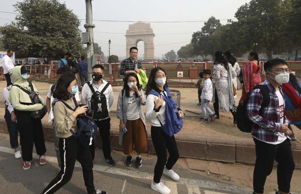 Foreign tourists wear masks to save themselves from pollution as they cross a road in New Delhi, India, Tuesday, Nov. 12, 2019. A thick haze of polluted air is hanging over India's capital, with authorities trying to tackle the problem by sprinkling water to settle dust and banning some construction. The air quality index exceeded 400, about eight times the recommended maximum. (AP Photo/Manish Swarup)