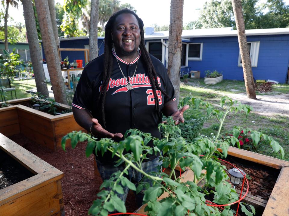 Corey "Goo" Paul wears a jersey and smiles while standing in his garden.