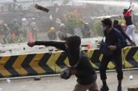 A protesters hurls a brick towards police trying to contain a rally in Jakarta, Indonesia, Thursday, Oct. 8, 2020. Thousands of enraged students and workers staged rallies across Indonesia on Thursday in opposition to a new law they say will cripple labor rights and harm the environment. (AP Photo/Achmad Ibrahim)