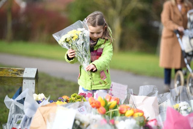 Noelle Simmons, four, leaves a floral tribute outside the home of Captain Sir Tom Moore in Marston Moretaine, Bedfordshire 