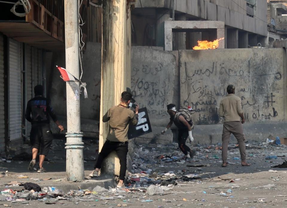 Anti-government protesters throw a Molotov cocktail toward riot police during clashes on Rasheed Street, Baghdad, Iraq, Tuesday, Nov. 26, 2019. (AP Photo/Khalid Mohammed)