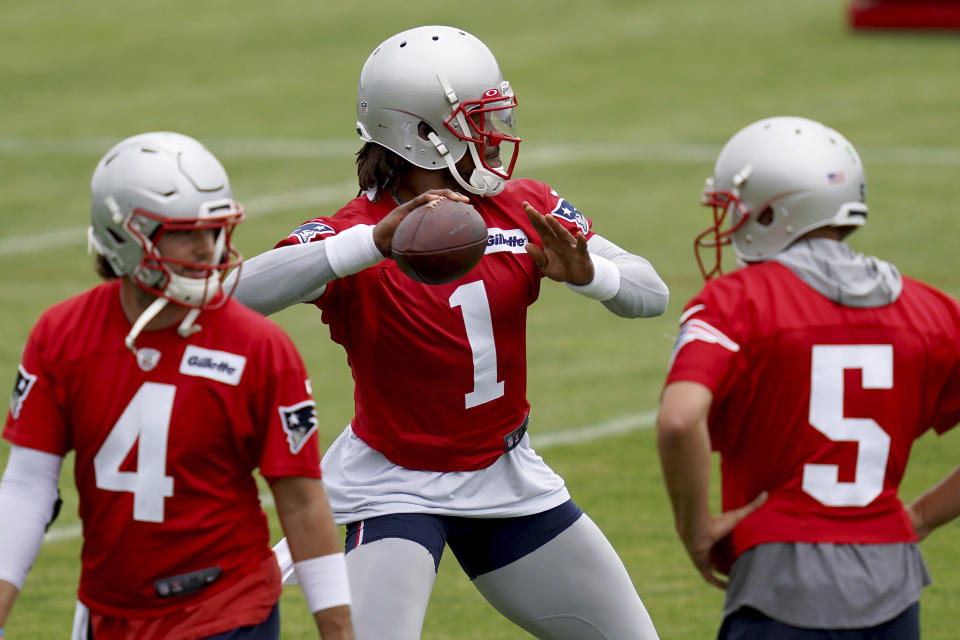New England Patriots quarterback Cam Newton throws a pass as Jarrett Stidham (4) and Brian Hoyter (5) look on during NFL football practice in Foxborough, Mass., Friday, June 4, 2021. (AP Photo/Mary Schwalm)
