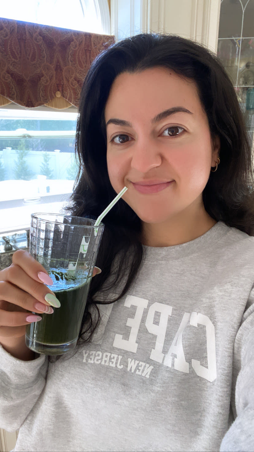 The author smiling and holding a glass of Athletic Greens