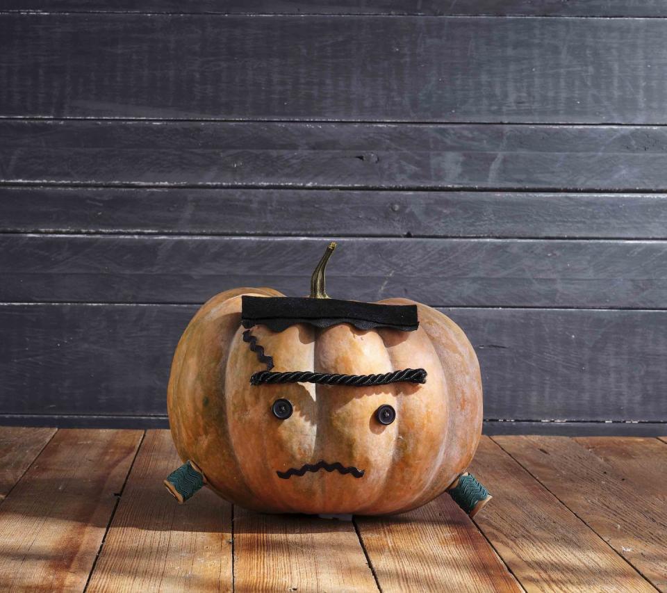 <p>Is he friendly or is he not?!?! With rickrack spool bolts how could he be anything other than sweet and cuddly.<strong><br></strong></p><p><strong>Make the pumpkin:</strong> Cut a length of extra-large black rickrack. Cut a piece of black felt the same length and attach it to the rickrack so that only the bottom “ruffles” are showing. Attach the top of a flat-shaped heirloom pumpkin for hair. Attach two small black buttons to the center of the pumpkin with hot-glue for eyes. Attach a length of thick black cording above the eyes with hot-glue for eyebrow. Attach lengths of medium-size black rickrack to pumpkin with hot-glue for scar and mouth. Wrap two wooden spools with green rickrack and attach to the bottom sides of pumpkin with hot-glue for bolts.</p>