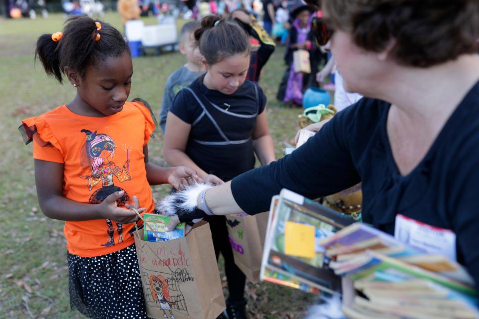 Second grader Genesis Duncan receives a book during trunk or treat at Sabal Palm Elementary in Tallahassee, Fla. Tuesday, Oct. 30, 2018. 