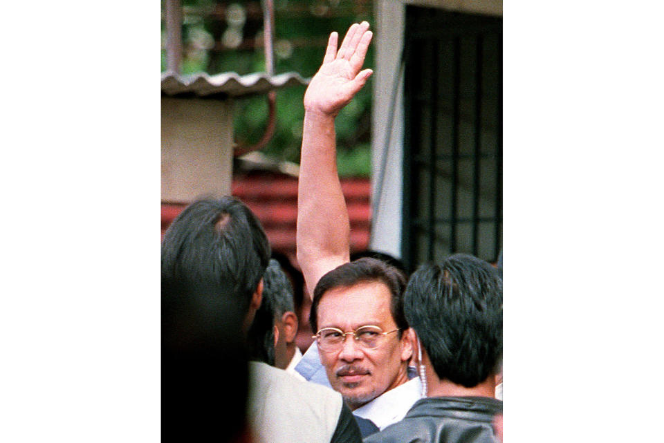 FILE - With a blackened left eye, former Deputy Prime Minister Anwar Ibrahim waves to supporters as he is led into Petaling Jaya court to be charged in Kuala Lumpur, Sept, 30, 1998. Malaysia's king on Thursday, Nov. 24, 2022, named Anwar as the country's prime minister, ending days of uncertainties after divisive general elections produced a hung Parliament. (AP Photo/Ed Wray, File)