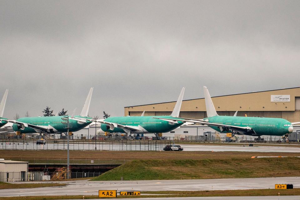 Three green Boeing 777X jets stationed at a production facility.