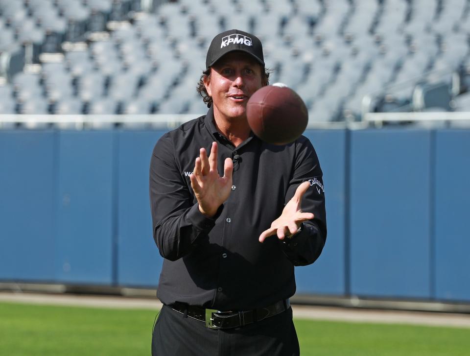 Phil Mickelson plays with a football at Soldier Field in 2018.