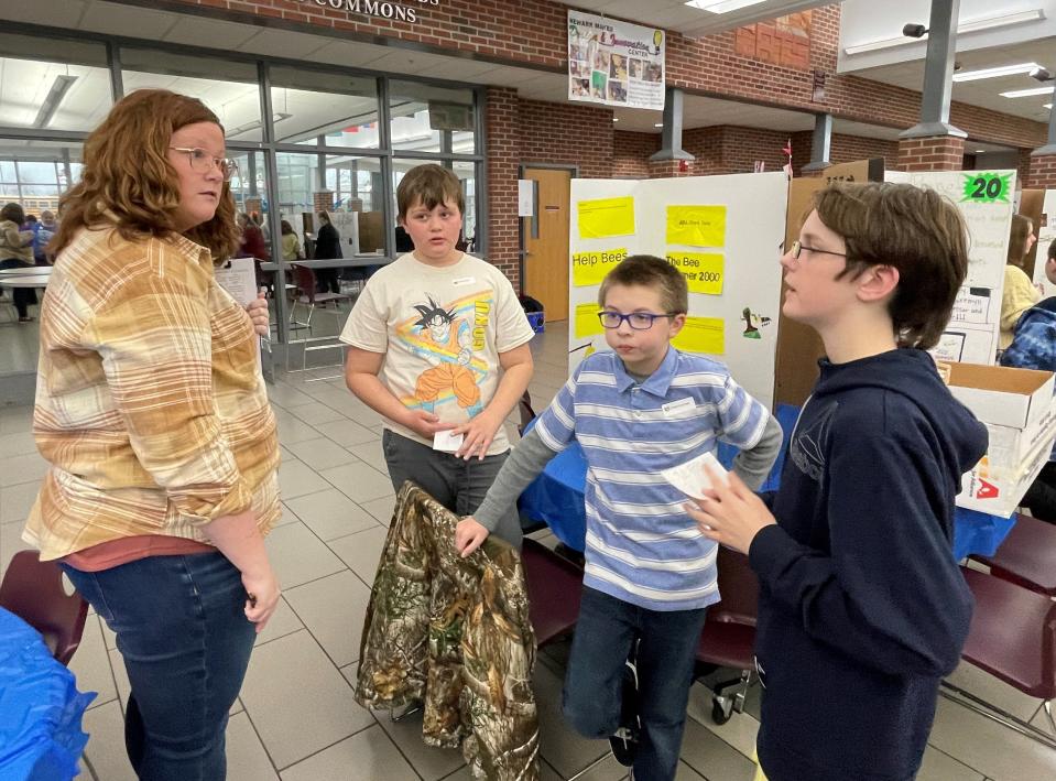 Jayme Blackstone, one of the judges at the Young Entrepreneur Pitch Challenge for Newark elementary students, listens as, from left, Connor Zeller, Joseph Kennedy and Gregory Purtell of Cherry Valley promote their "Bee Warmer."