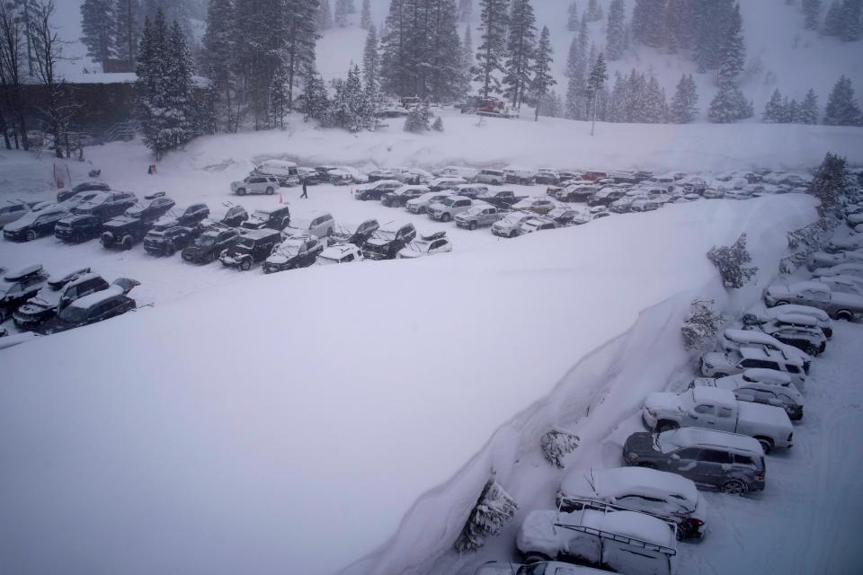 A person walks through the parking area of the Alpine Base Area at Palisades Tahoe during a winter storm Friday, Feb. 24, 2023, in Alpine Meadows, Calif.