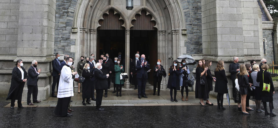 Mourners including the President of Ireland Michael D. Higgins, applauds as the funeral cortege of the the former Northern Ireland lawmaker and Nobel Peace Prize winner John Hume leaves following the funeral Mass at St Eugene's Cathedral in Londonderry, Northern Ireland, Wednesday, Aug. 5, 2020. Hume was co-recipient of the 1998 Nobel Peace Prize with fellow Northern Ireland lawmaker David Trimble, for his work in the Peace Process in Northern Ireland. Masks are worn due to the ongoing Coronavirus outbreak . (AP Photo/Peter Morrison)