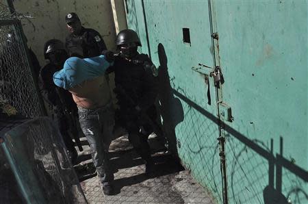 An inmate is escorted by riot policemen after a gunfight in the Tuxpan prison in Iguala, in the Mexican State of Guerrero January 3, 2014. REUTERS/Jesus Solano