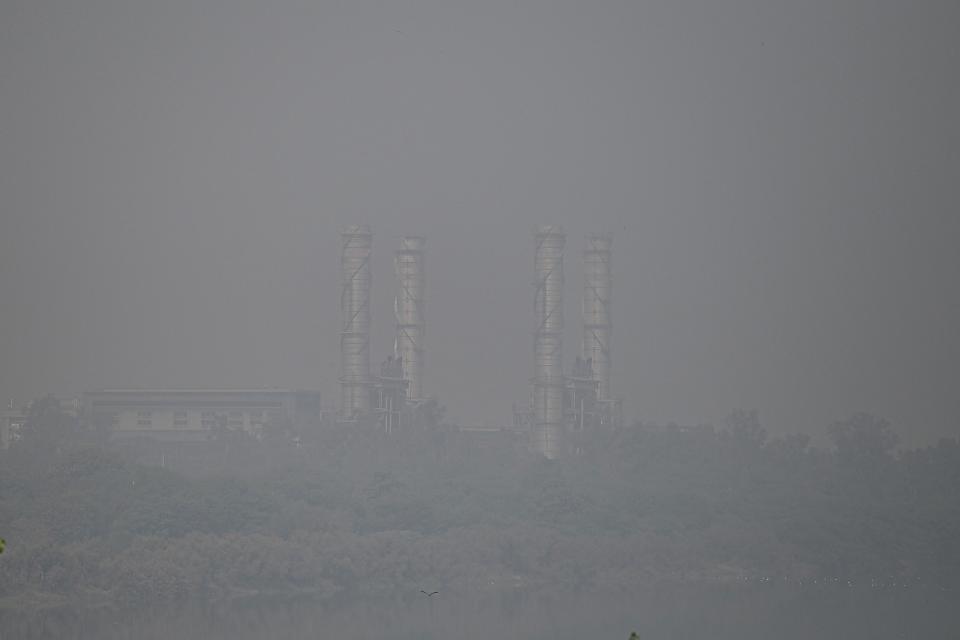 <p>Industrial chimneys are pictured amid heavy smog in New Delhi on November 16, 2021. (Photo by Money SHARMA / AFP) (Photo by MONEY SHARMA/AFP via Getty Images)</p> 