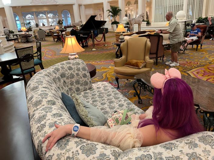 jenna lounging on a couch in the lobby of the grand floridian resort listening to the piano player