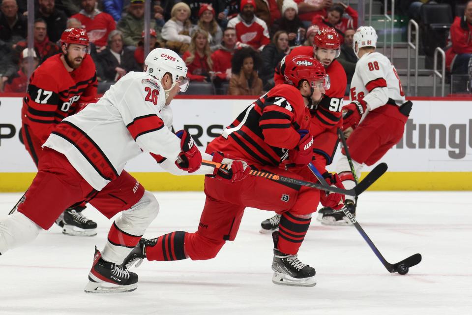 Dylan Larkin (71) of the Detroit Red Wings tries to control the puck in front of Paul Stastny (26) of the Carolina Hurricanes during the first period at Little Caesars Arena on December 13, 2022 in Detroit, Michigan.