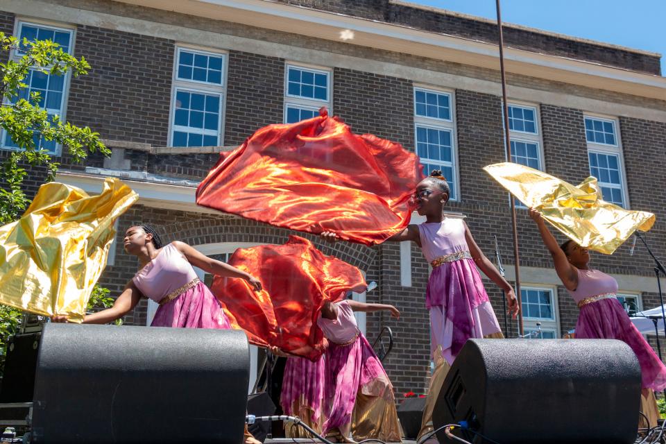 Restoration dance team members Genesis, Amajah, London, Jazelyn and Reubetta dance with orange and yellow flags on Saturday, June, 18, 2022, during the Juneteenth festival held at Bradley Academy Museum and Cultural Center.