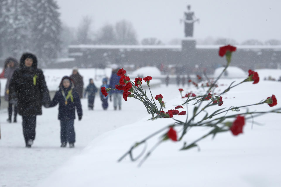 People walk in snowfall to place flowers to the Motherland monument at the Piskaryovskoye Cemetery where most of the Leningrad Siege victims were buried during World War II, in St. Petersburg, Russia, Saturday, Jan. 26, 2019. People gathered to mark the 75th anniversary of the battle that lifted the Siege of Leningrad. The Nazi German and Finnish siege and blockade of Leningrad, now known as St. Petersburg, was broken on Jan. 18, 1943 but finally lifted Jan. 27, 1944. More than 1 million people died mainly from starvation during the 900-day siege. (AP Photo/Dmitri Lovetsky)