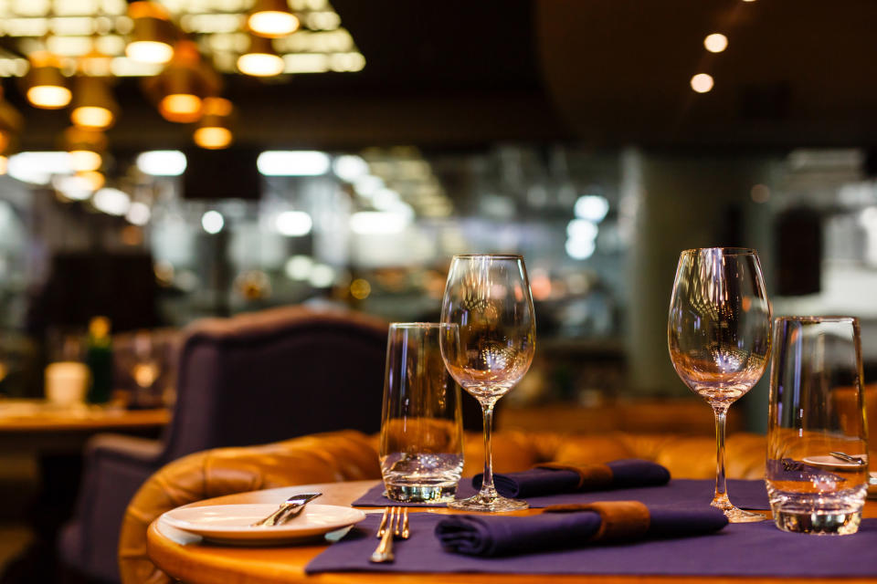 A stock image of a set table with two wine glasses overlooking a restaurant