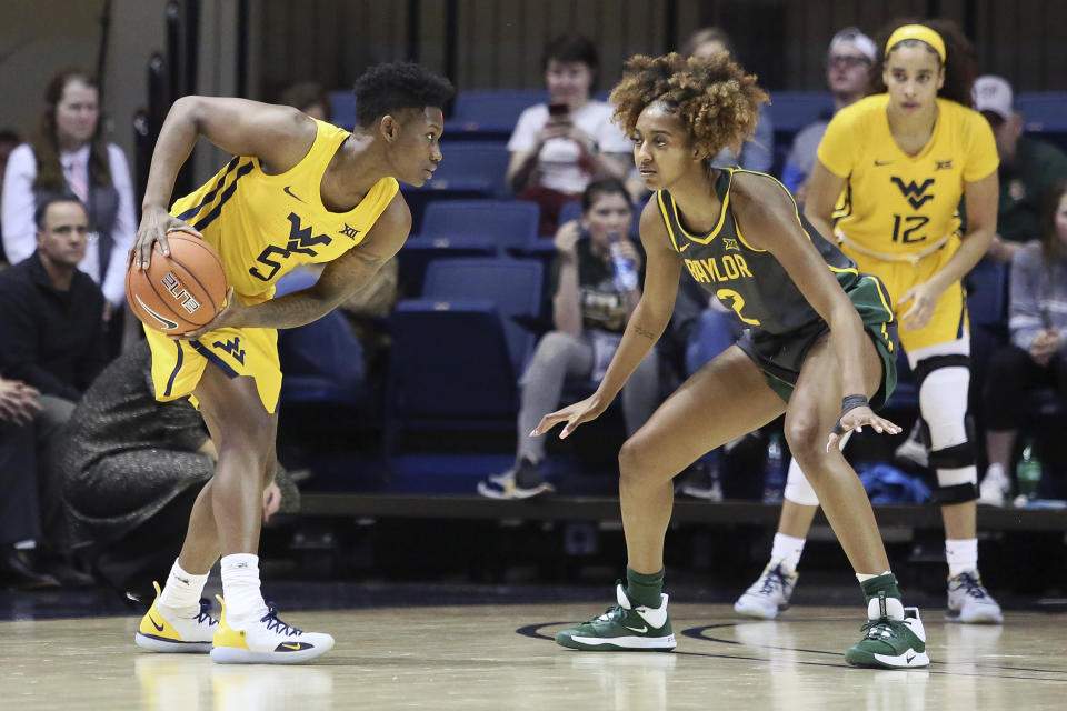 West Virginia guard Tynice Martin (5) looks to pass the ball while defended by Baylor guard DiDi Richards (2) during the first half of an NCAA college basketball game Monday, Feb. 24, 2020, in Morgantown, W.Va. (AP Photo/Kathleen Batten)