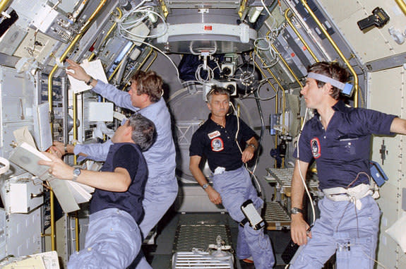 STS-9 crew members working on science experiments inside the European Spacelab 1 module, November 1983.