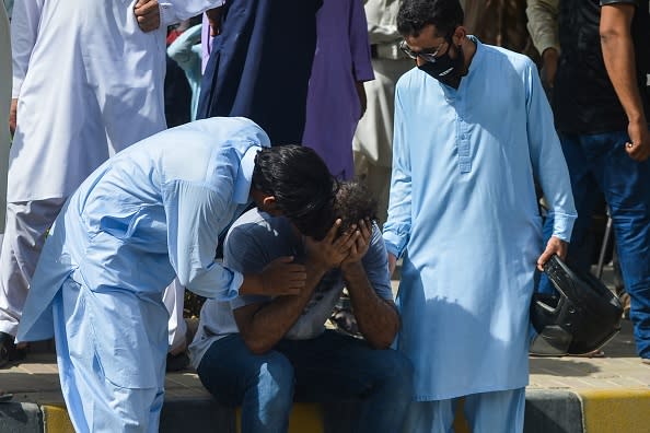 People comfort a relative of a victim near the site after a Pakistan International Airlines aircraft crashed in a residential area in Karachi.