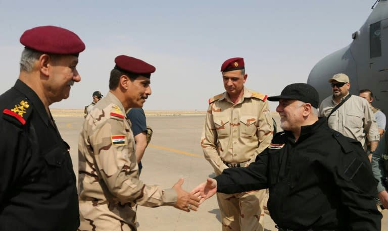 A handout picture released by the Iraqi prime minister's press office on July 9, 2017, shows Iraqi Prime Minister Haider al-Abadi (R) shaking hands with police and army officers upon his arrival in Mosul