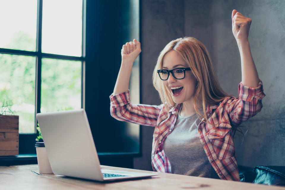 Young woman celebrating at laptop