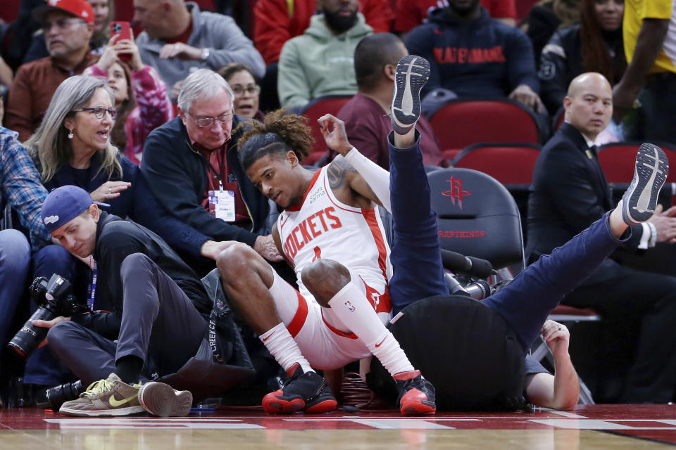 Houston Rockets guard Jalen Green, center, is helped by fans after falling into photographers after a play against the Portland Trail Blazers during the first half of an NBA basketball game Saturday, Dec. 17, 2022, in Houston. (AP Photo/Michael Wyke)