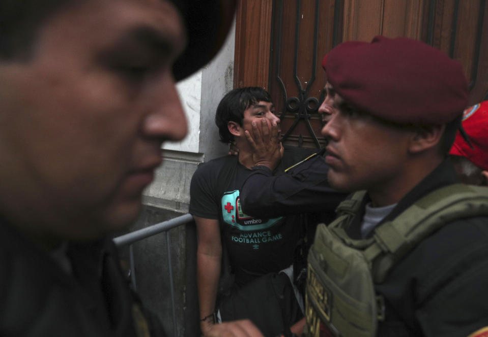 A supporter of Keiko Fujimori, the daughter of Peru's former President Alberto Fujimori and opposition leader, is held back by police officers outside a courtroom in Lima, Peru, Tuesday, Jan. 28, 2020. A Peruvian judge ordered 15 months of preventive detention for Keiko Fujimori while she is investigated for alleged money laundering related to the Brazilian construction company Odebrecht. (AP Photo/Martin Mejia)