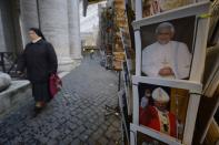 A nun passes by posters showing Pope Benedict XVI and Pope John Paul II at a Vatican shop after it was announced that Pope Benedict XVI will resign on February 11, 2013